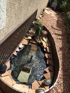 a wooden bench sitting next to a small pond in the middle of a garden area