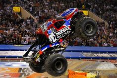 a monster truck is in the air over some dirt