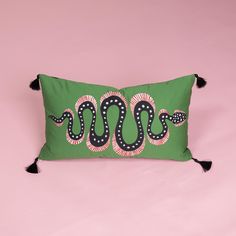 a green pillow with a black snake on the front and white dots on the back