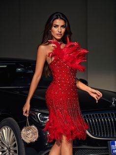 a woman in a red dress is standing next to a car