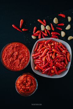 two bowls filled with red chili beans next to some peanuts