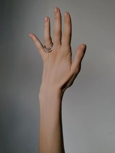 a person's hand with a ring on it, reaching up to the sky