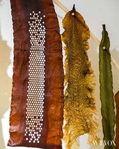 three scarves hanging on a clothes line, one is brown and the other is green