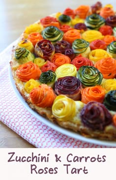 a colorful pizza on a plate with the words zucchini & carrots rose tart