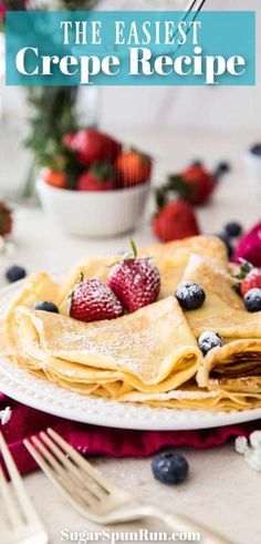 crepes with berries and powdered sugar on top are sitting on a white plate