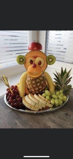 a plate with grapes, cheese and fruit on it that is shaped like a monkey