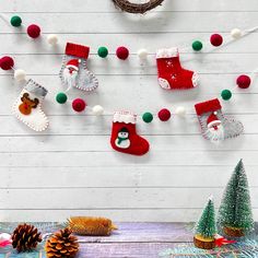 christmas stockings and decorations hanging on a white wooden wall with pine cones, fir trees and other holiday items