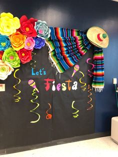 a blackboard with colorful paper flowers and tassels hanging from it's sides