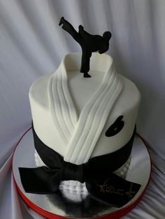 a cake with a karate figure on top and black ribbon around the edge, sitting on a red plate