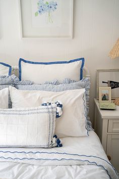 a white bed with blue trim and pillows