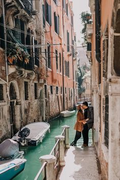 two people standing on the edge of a narrow canal