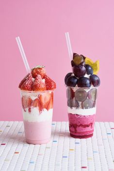 two cups filled with fruit and yogurt next to each other on a table