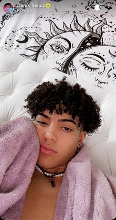 a woman laying in bed under a blanket with her hand on her face and looking at the camera