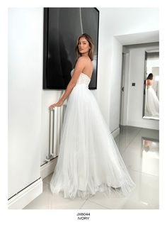 a woman standing in front of a black and white painting wearing a wedding dress with an open back