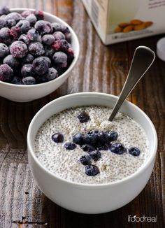 two bowls filled with oatmeal and blueberries next to a carton of milk