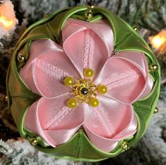 a pink and green flower ornament hanging from a christmas tree