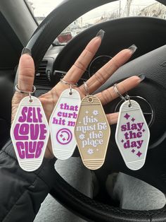 three keychains with sayings on them are hanging from the dashboard of a car