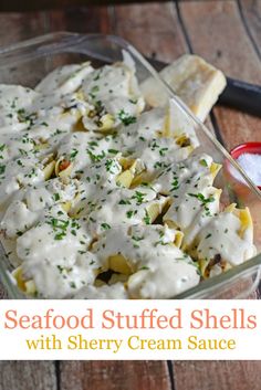 a glass dish filled with seafood stuffed shells and creamy cream sauce on a wooden table