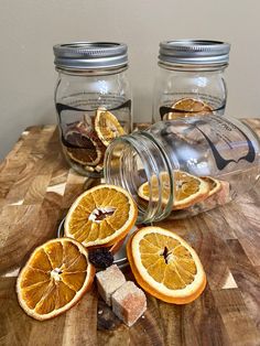 some oranges are cut in half and placed on a cutting board next to two jars