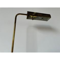 a lamp that is on top of a white wall next to a black and gold pole