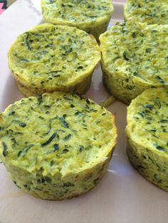 four muffins with spinach and cheese are on a white plate, ready to be eaten