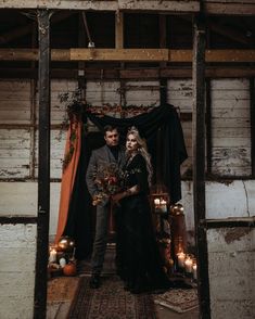 a man and woman standing next to each other in front of a doorway with candles