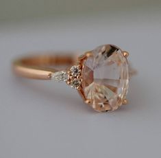 a close up of a ring with an oval shaped stone and two small diamonds on the side