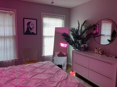 a bedroom with pink walls, white furniture and a large mirror on the wall above the bed