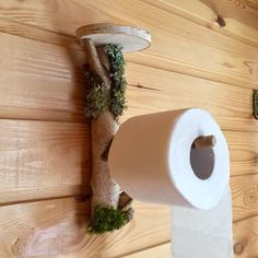 a roll of toilet paper sitting on top of a wooden floor next to a tree