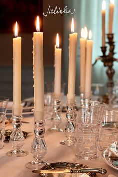 a table topped with lots of candles and dishes filled with glasses next to each other