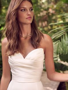 a beautiful woman in a white dress posing for the camera with her hand on her hip