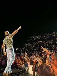 a man standing on top of a stage with his arms in the air while holding a microphone