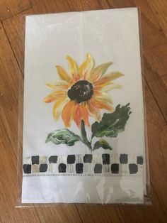 a piece of white paper with a yellow flower on it sitting on top of a wooden floor