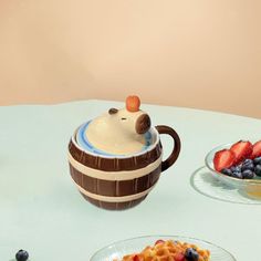 two plates with waffles and fruit on them sitting next to a teapot