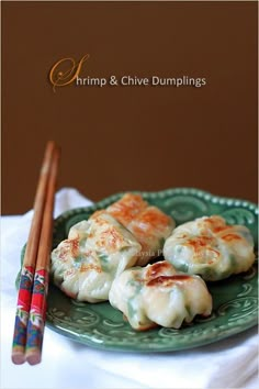 some dumplings are on a green plate with chopsticks