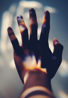 a person's hand with their fingers extended up in front of a blurry background