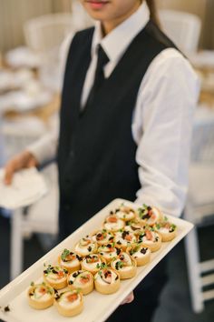 a woman holding a tray with small appetizers on it