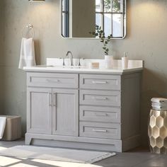 a bathroom with a sink, mirror and towels on the rack in front of it