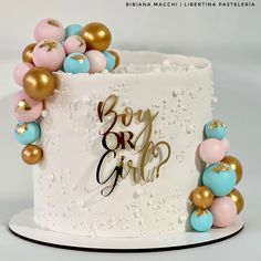 a white cake with gold and blue decorations on it's side, decorated with baby girl letters