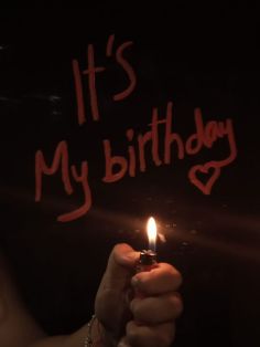 a person holding a lit candle with the words it's my birthday written on it