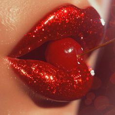 a woman's lips with red glitter on them and an apple sticking out of the lip