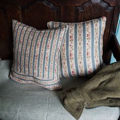 a pair of brown shoes sitting on top of a bed next to a pillow and jacket