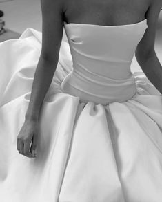 a woman in a white dress sitting on the floor with her hand under her skirt