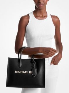 Crafted from pebbled leather in a structured silhouette, the Mirella tote features our iconic brand lettering and a polished logo charm for an ultra-luxe finish. With sleek top-handles and a woven crossbody strap, this bag will be your new daytime go-to. Wear it with denim and a classic white shirt. Brand Lettering, Classic White Shirt, Black Leather Tote Bag, Black Tote Bag, Leather Tote Bag, Classic White, Interior Details, Crossbody Strap, Pebbled Leather