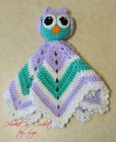 a crocheted owl sitting on top of a blanket