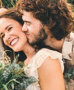 a man and woman are smiling while holding flowers