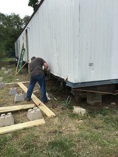 a man standing next to a white trailer with cement blocks on the ground in front of it