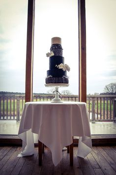 a black and white wedding cake sitting on top of a table next to a window