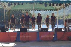 a group of people standing on top of a stage next to each other under a tent