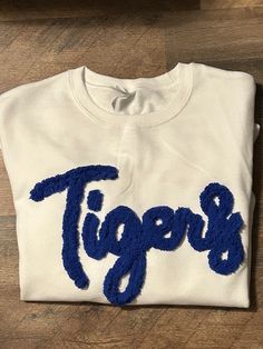 Show your school spirit in this cute sweatshirt. Comfort, casual and loose fitting, made on 50/50 cotton/poly blend shirts.  Embroidered chenille yarn, Tigers sweatshirt. This on a white sweatshirt with royal blue yarn.  Please message us if you have a custom color request and we will create a separate listing for custom requests.  You can follow us at the below link for chances to win giveaways and to see all of our latest creations.  https://www.facebook.com/groups/710060383256657/?ref=share&mibextid=S66gvF Chenille Sweatshirt, Kentucky Sweatshirt, Chenille Embroidery, School Spirit Wear, Mom In Law, Altered Clothing, Novelty Yarn, Letter Sweatshirt, Embroidery Tshirt